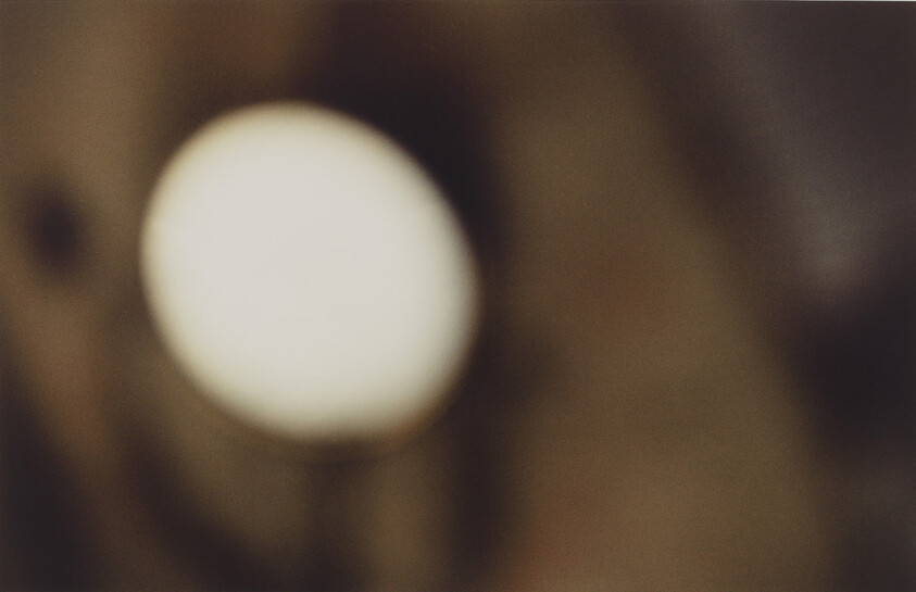 A blurry photograph with a large, out-of-focus white circle dominating the center against a dark, indistinct background.