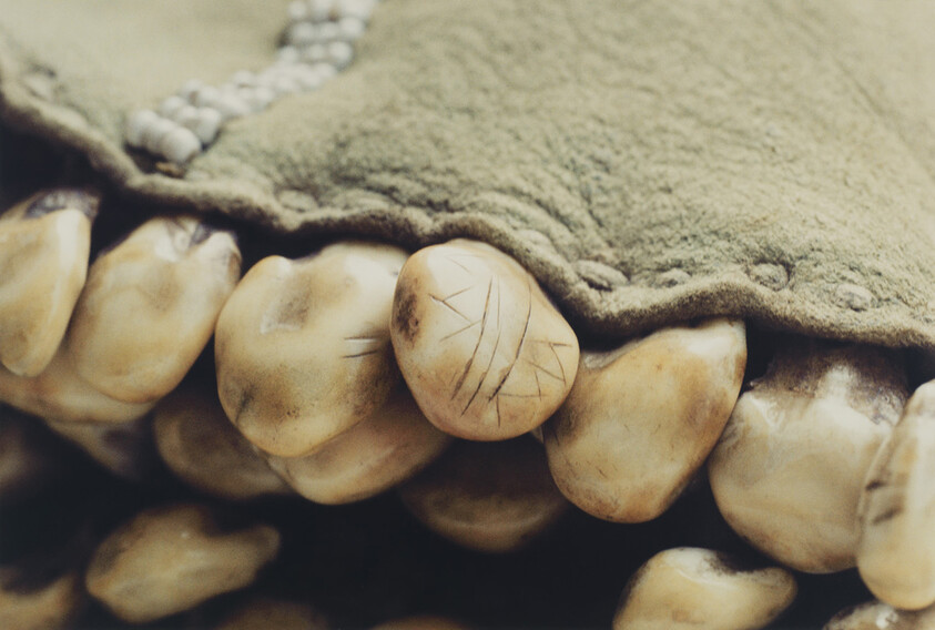 Close-up of carved bone beads with carved lines peeking from under a green cloth.