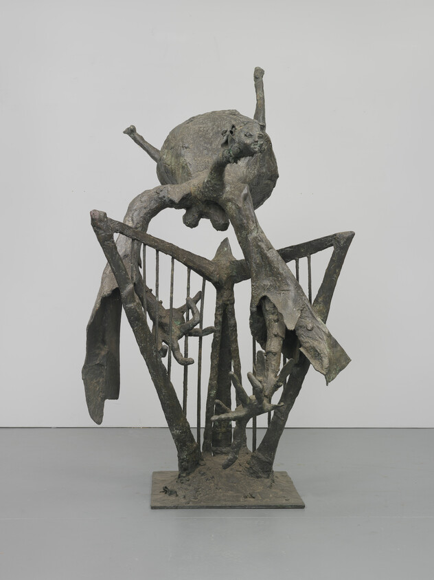 Abstract bronze sculpture of a twisted humanoid figure draped over a cage-like frame.