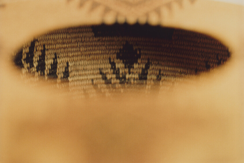 Close-up of a knit fabric with a dark oval hole revealing a floral pattern underneath.