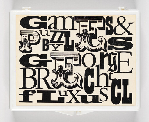 A white plastic box lid decorated with a dense collage of large black decorative letters.