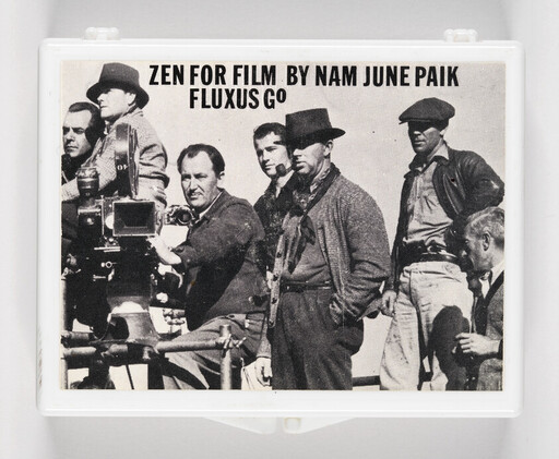 A group of men stand around a movie camera under the title "Zen for Film by Nam June Paik."