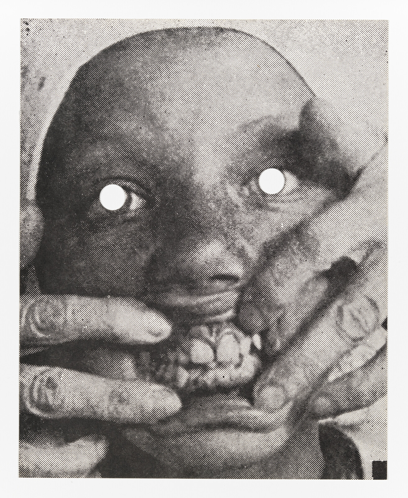 A close-up of a person with eye holes punched out as hands pull their mouth open revealing teeth.