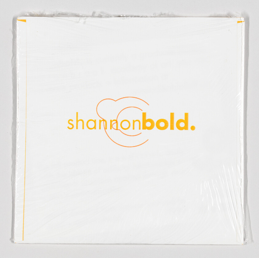 A wrapped canvas with the text "shannonbold." in orange, featuring a stylized heart design, against a white background. The canvas edges are visible, with the wrapping material slightly torn at the corners.
