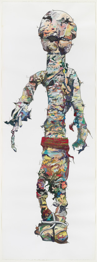Tall colorful humanoid figure made of torn fabric and paint, standing with feet bound.