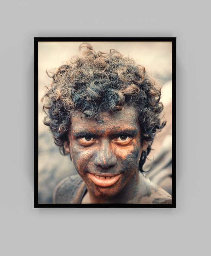 Young person with curly hair and a dirt-smeared face looking directly at the camera.