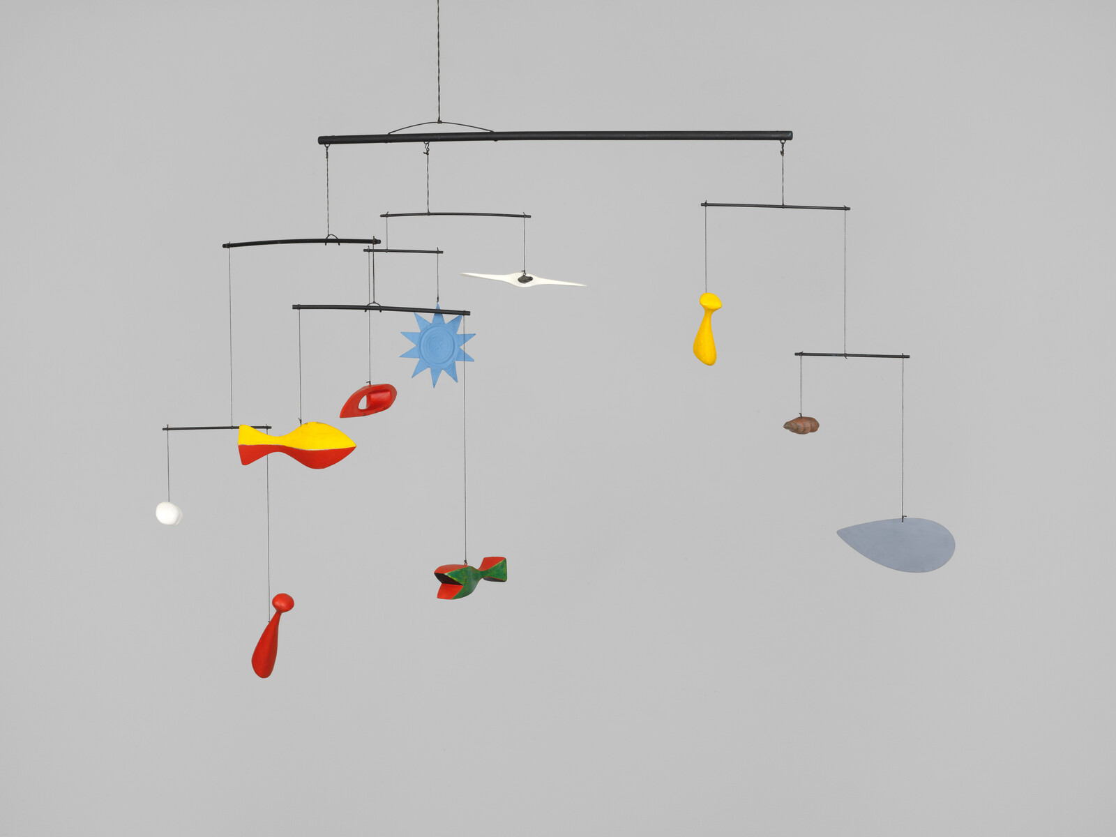 A hanging mobile with colorful abstract shapes and balanced metal rods against a gray background.