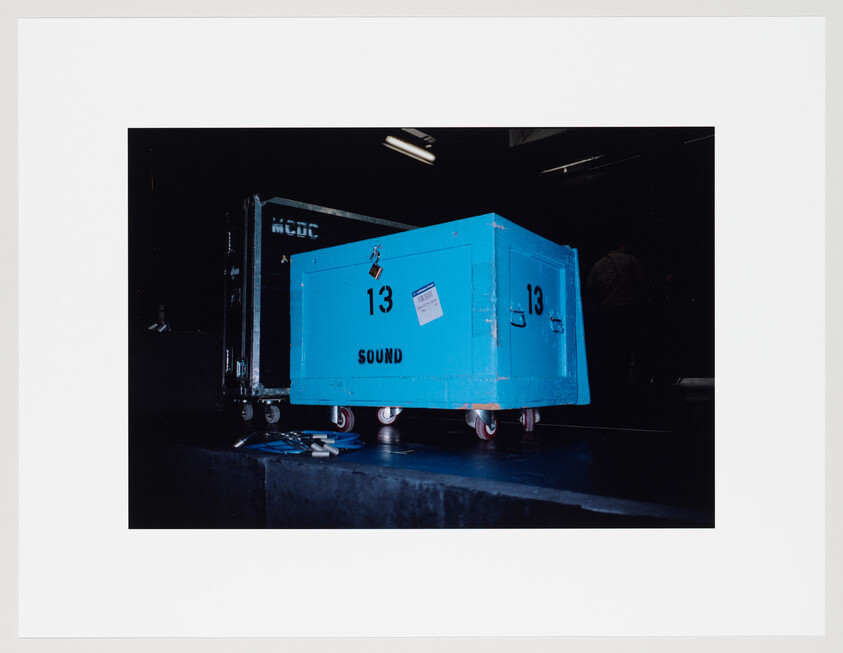 A blue equipment case labeled "13 SOUND" sits on stage wheels with cables nearby.