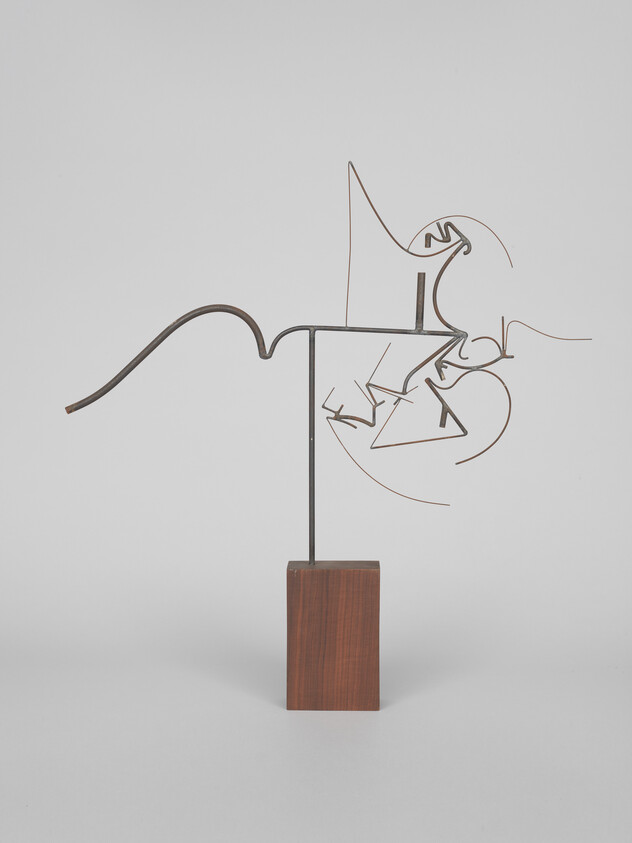 Abstract thin metal wire sculpture with looping shapes mounted on a rectangular wooden base.