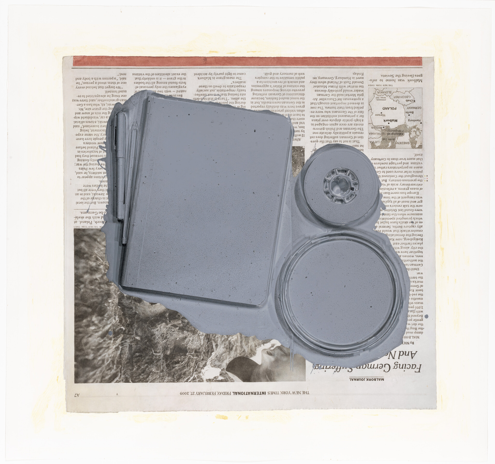 A gray paint spill covers a notebook, tape rolls, and pens on a newspaper.