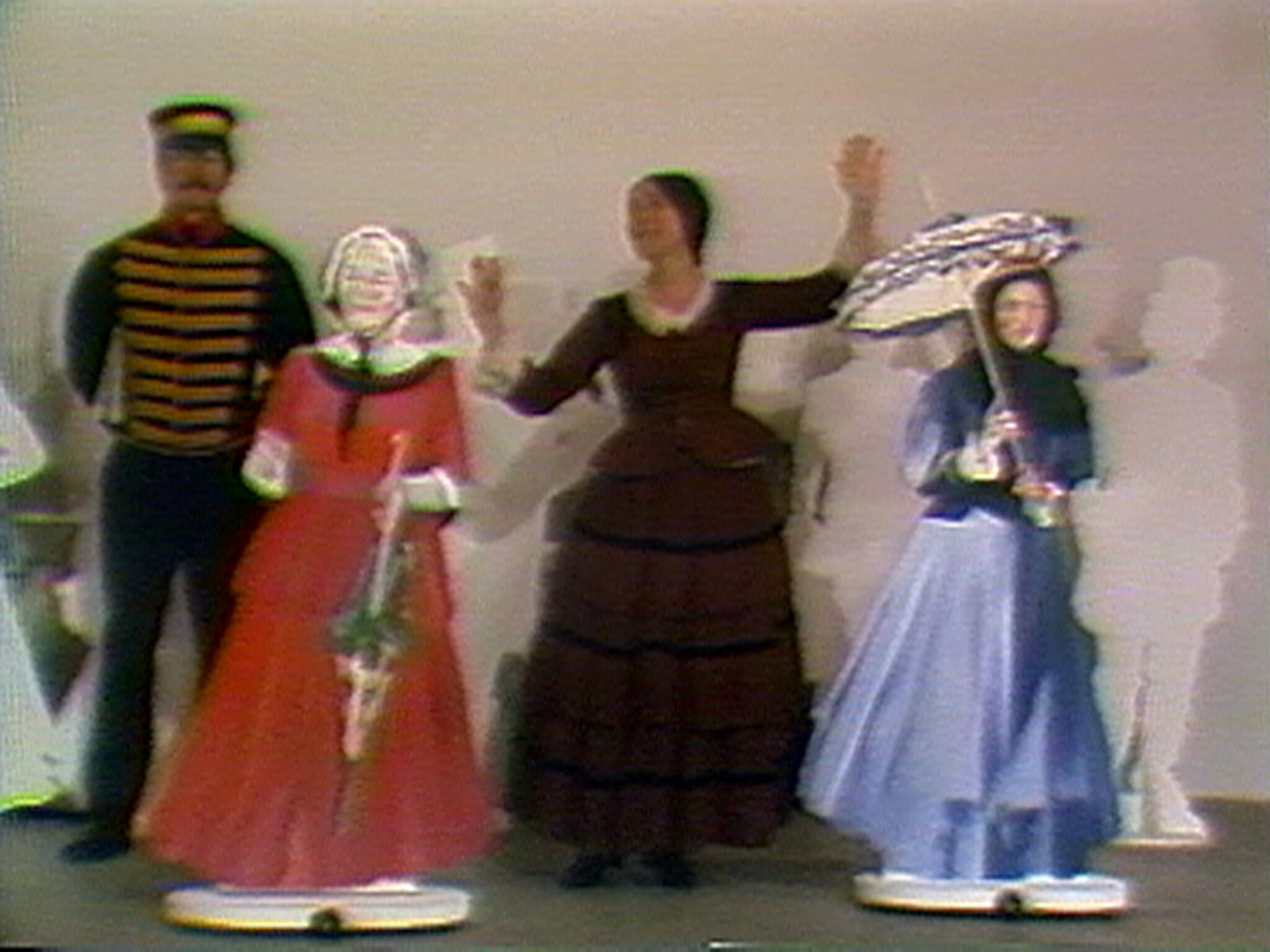 Woman standing between two period-dressed figures, raising her arms while one figure holds a parasol.