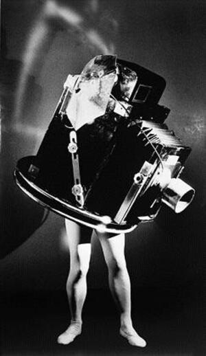 A person stands with their body mostly hidden inside a large, bulky mechanical object, only their legs visible.