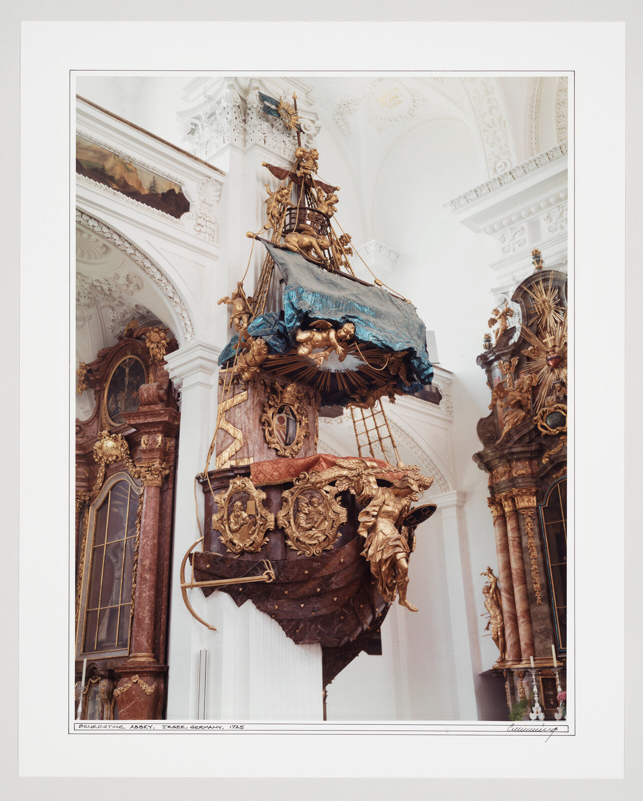 Ornate gilded ship-shaped pulpit suspended inside a richly decorated Baroque church interior.