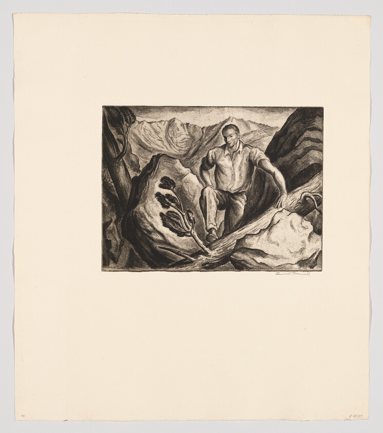 A man climbs over large rocks with mountains in the background.