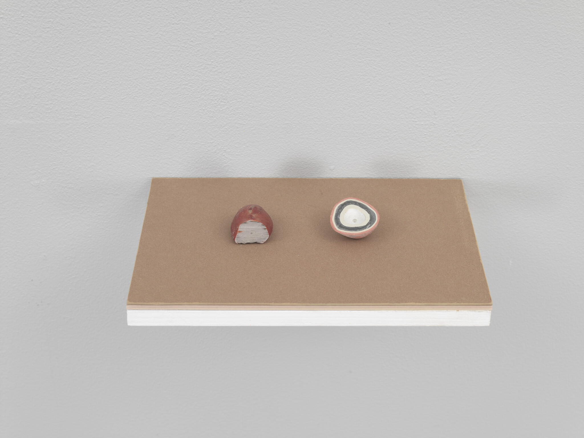 A small wall shelf holds two half-round clay objects, one showing layered concentric rings.