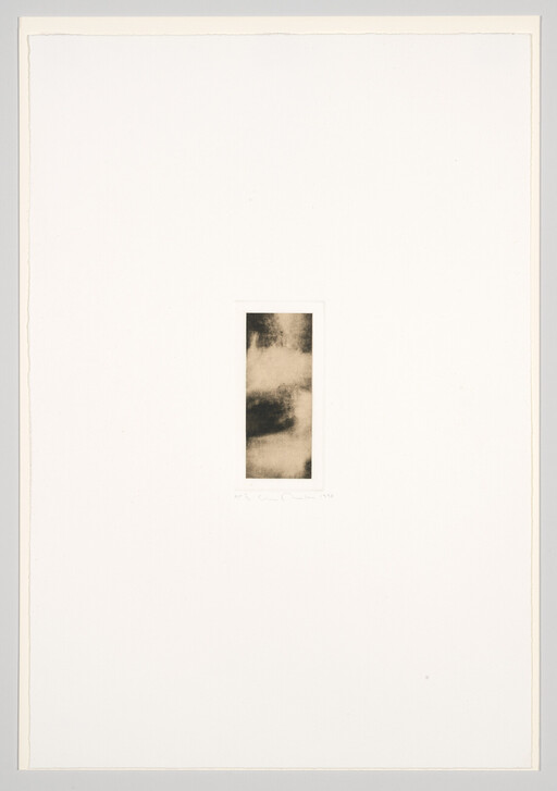 A small vertical abstract dark-toned print resembling clouds is centered on a large white sheet.