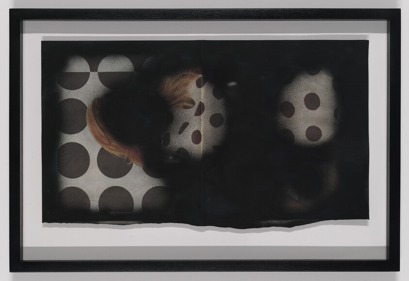 Framed artwork showing dark spray-painted overlay partially obscuring polka-dot pattern and a woman's face.