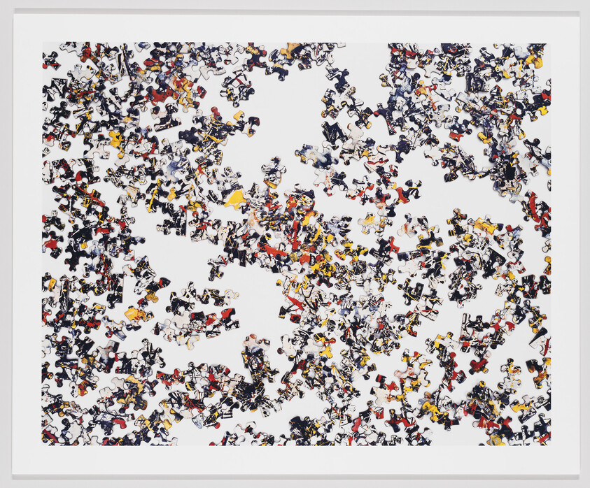 Scattered jigsaw puzzle pieces with black, red, and yellow patterns spread across a white background.