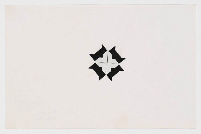 Small black-and-white geometric star made from cut paper sits centered on a large white sheet.