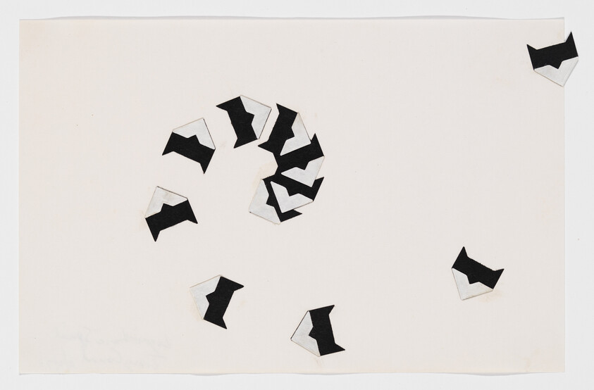 Black-and-white folded paper shapes arranged in a loose spiral and scattered on a white sheet.