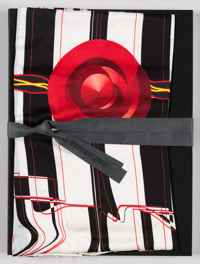 Folded scarf with red circular graphic and black-and-white striped pattern tied with gray ribbon.