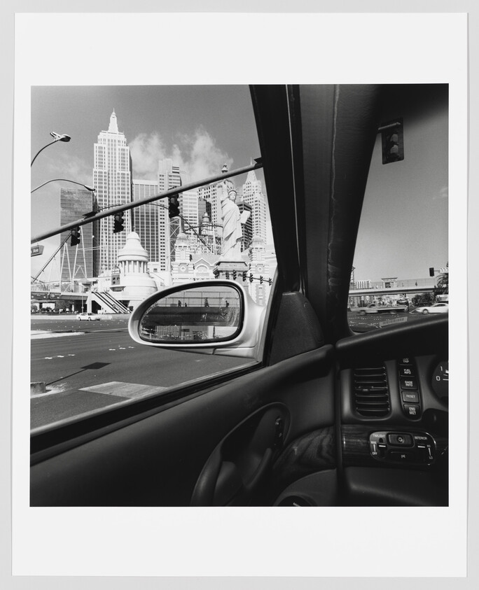 View from a parked car showing the Las Vegas New York-New York skyline and Statue of Liberty replica.