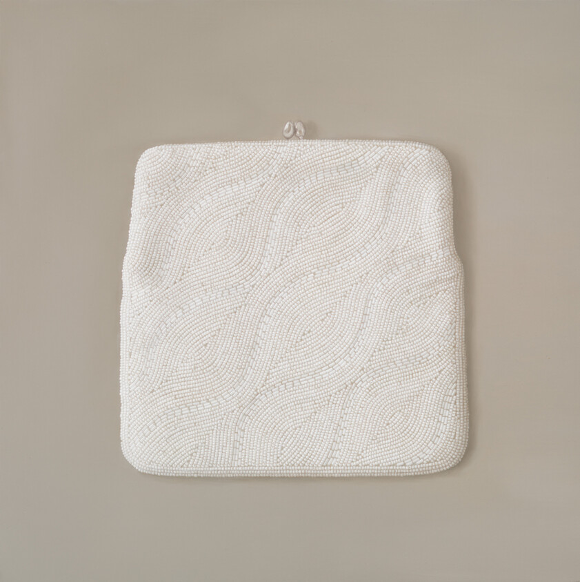 White beaded clutch purse with swirling bead pattern and small metal clasp on neutral background.