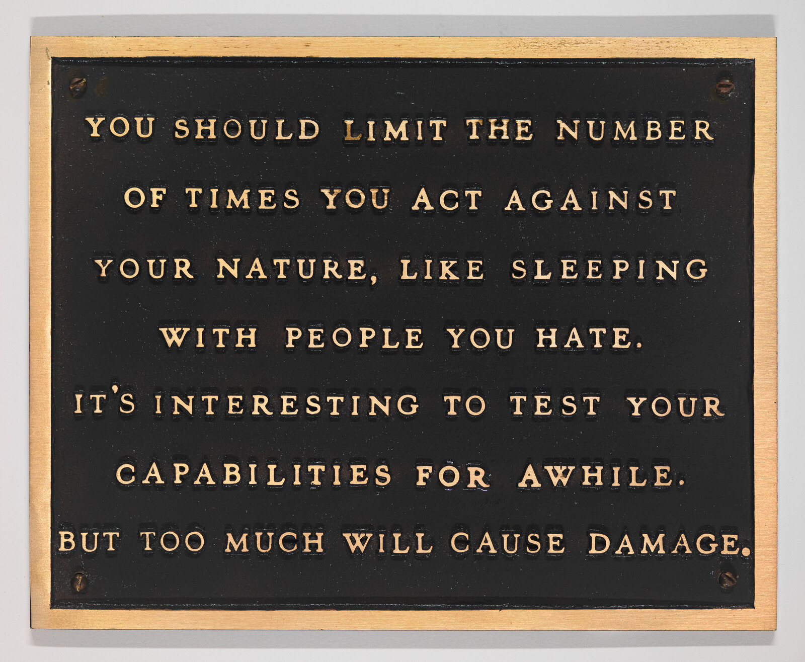A black plaque with gold letters advising to limit acting against your nature, like sleeping with people you hate.