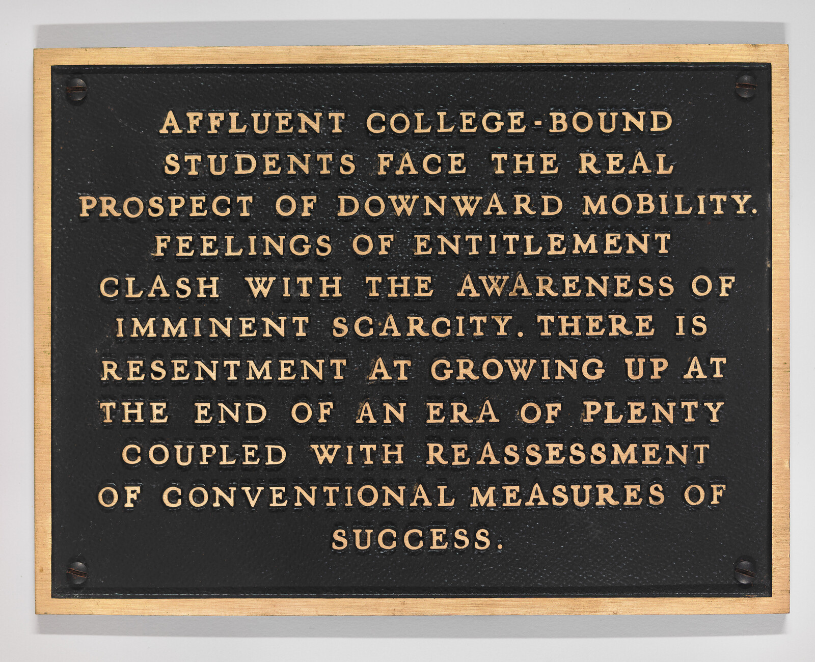 A brass-bordered plaque warns affluent college-bound students they face the real prospect of downward mobility.