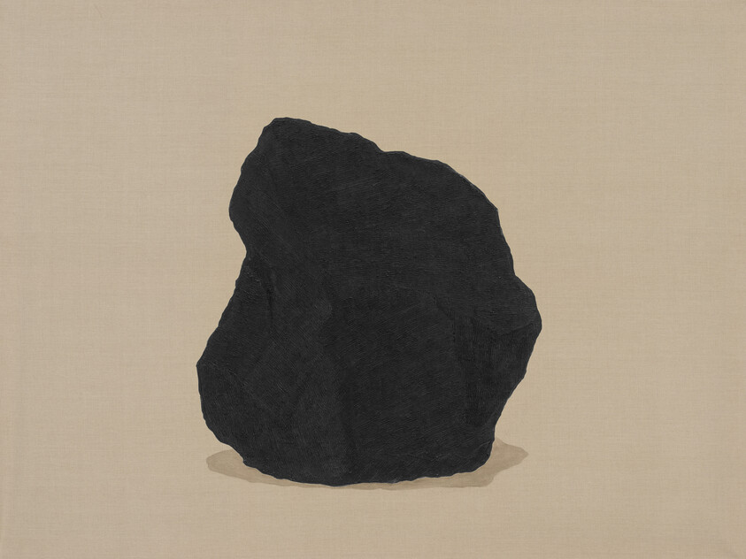 A large rough black rock resting on a beige fabric-like background.