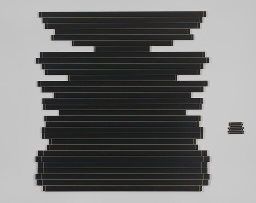 Stacked black horizontal panels form an irregular rectangle on a white wall with a small separate stack to the right.