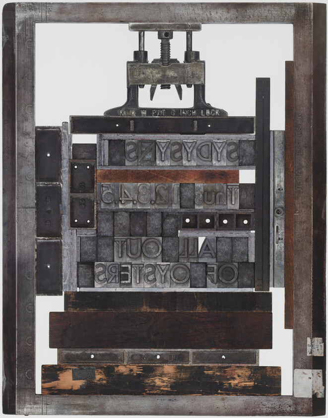 Letterpress printing form with metal type and wood blocks arranged inside a metal frame.