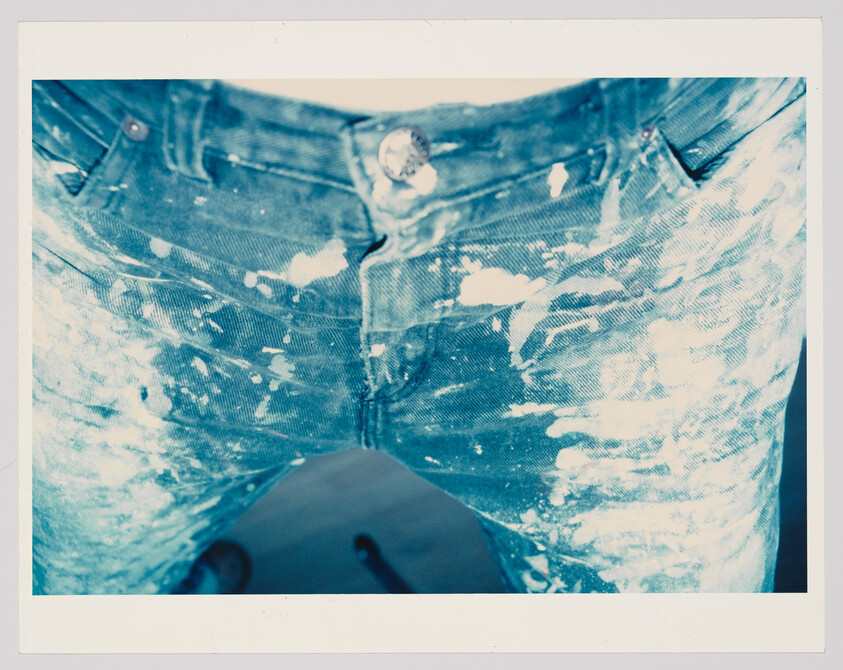 Blue jeans covered in white paint splatters across the front and thighs.