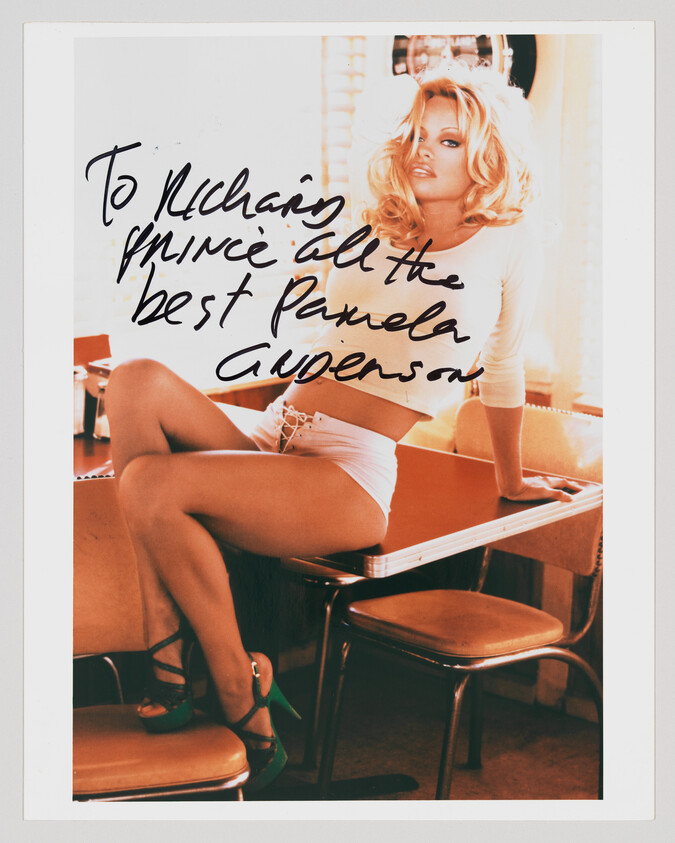 Glamour portrait of a woman lounging on a diner table with a handwritten dedication across the photo.
