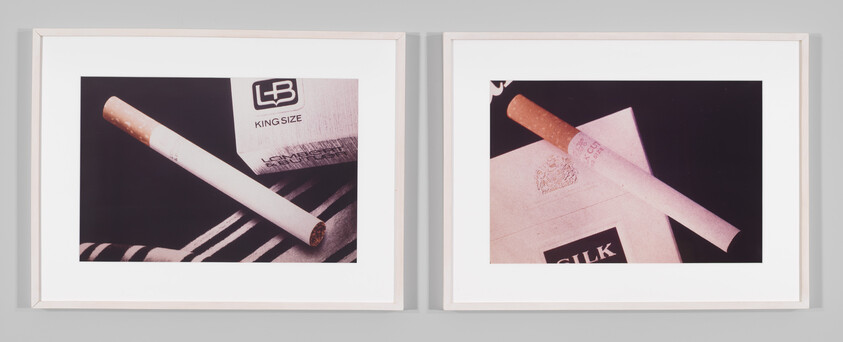 Two framed photos show cigarettes resting on packaging and fabric, displayed side by side.
