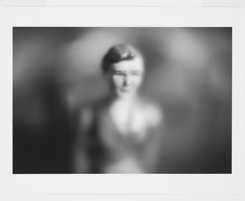 Blurred black-and-white portrait of a person with short hair and indistinct features.