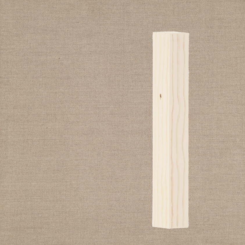 A tall unfinished wooden beam standing vertically against a plain beige fabric background.
