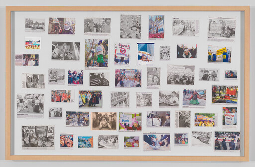 A framed bulletin board displaying many photos and newspaper clippings of protests and demonstrations.
