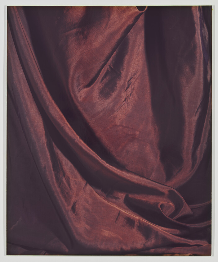 Maroon satin fabric draped with soft folds and subtle highlights.