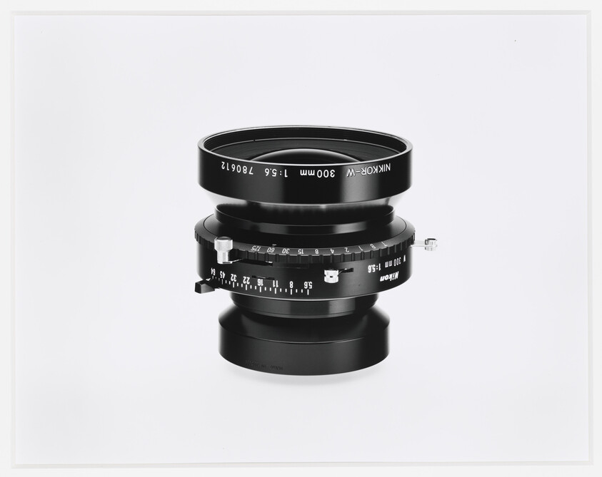 A black camera lens with marked aperture and focus rings on a white background.
