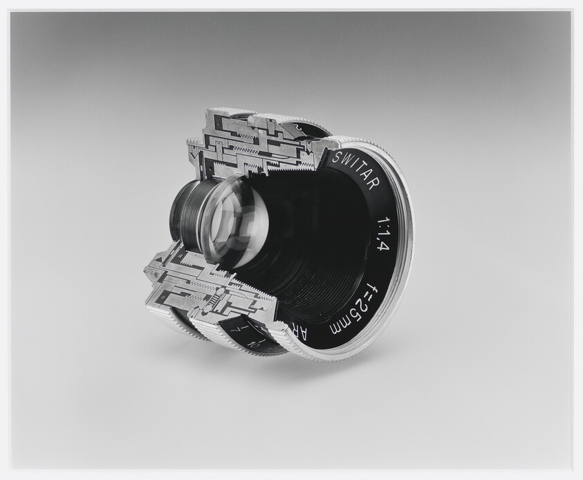 Cutaway Switar 25mm f/1.4 camera lens showing internal glass elements and mechanical structure.
