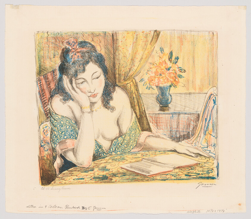 A woman leaning on her hand and reading a book at a table with a vase of flowers.