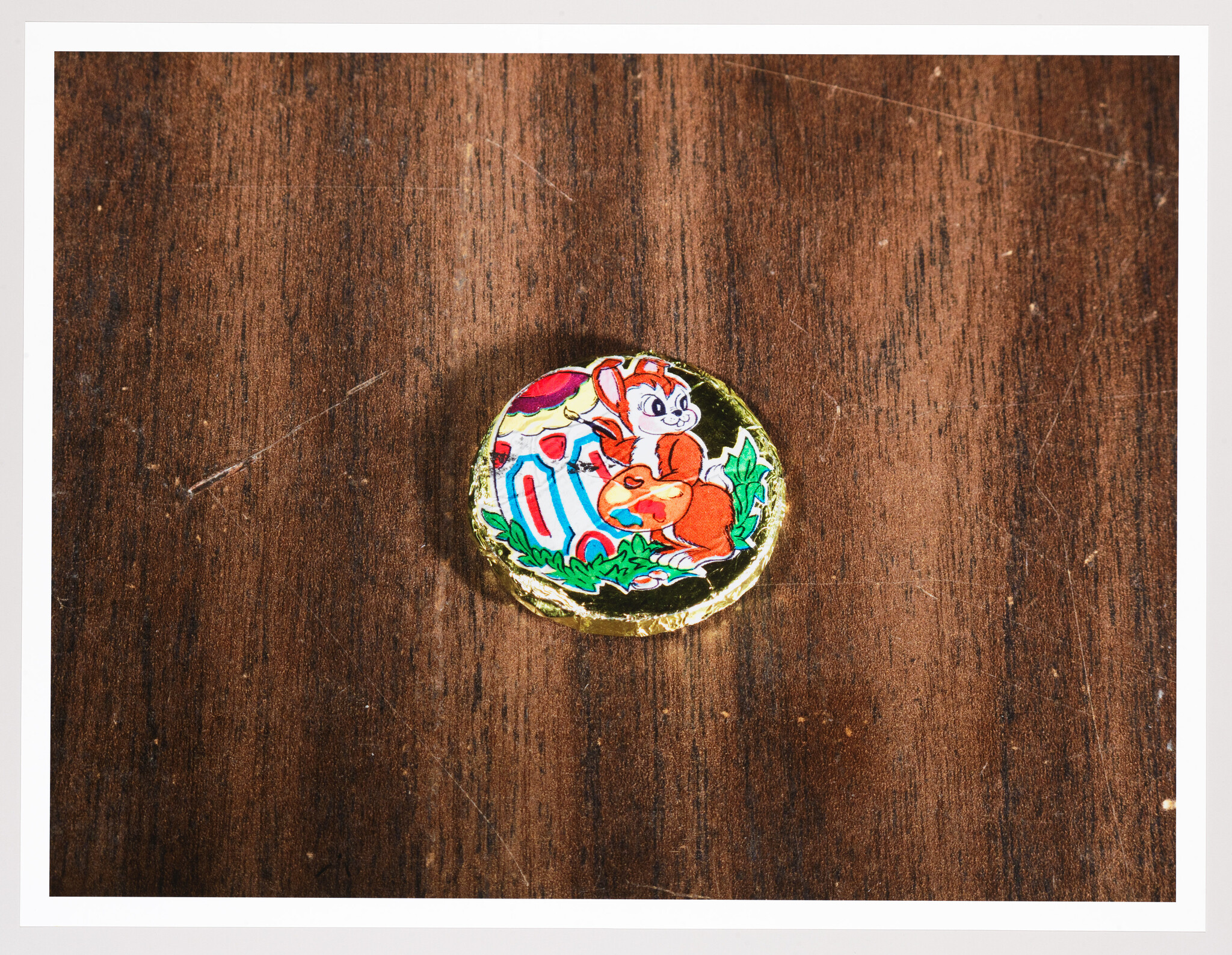 A colorful, round sticker featuring a cartoon illustration of a squirrel with an acorn on a wooden surface.
