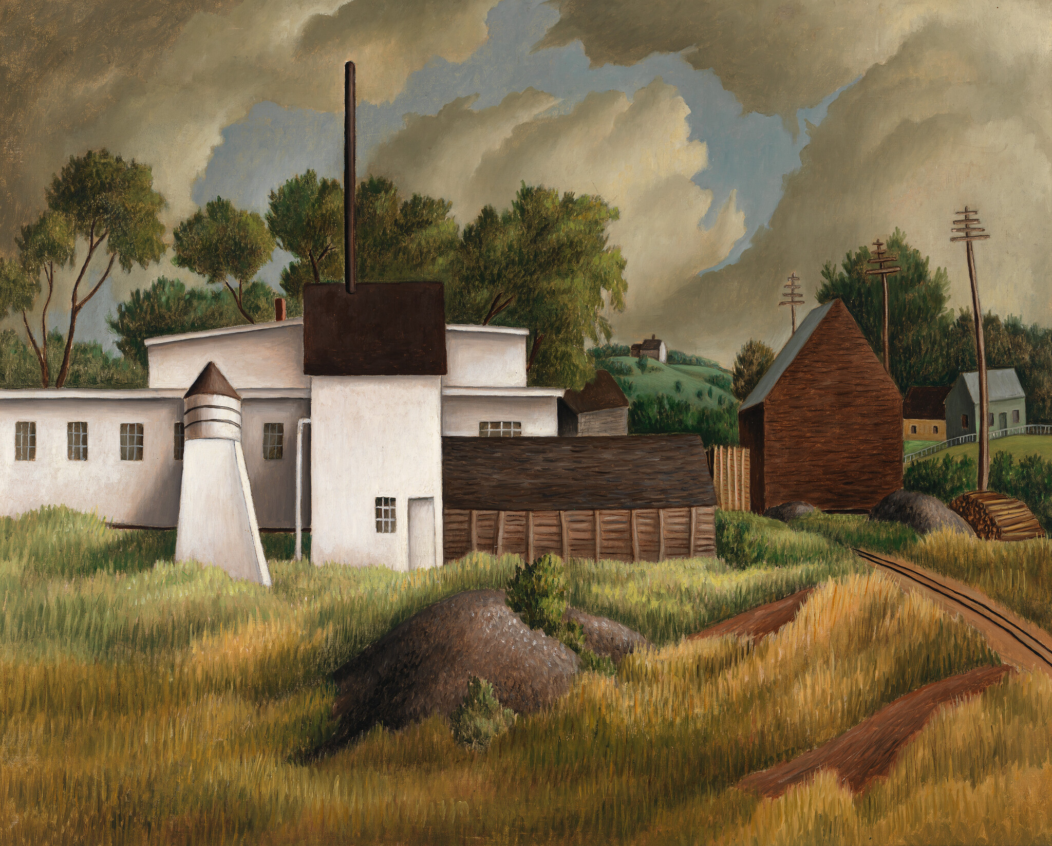 White industrial building and brown barn sit among tall golden grass under heavy storm clouds.