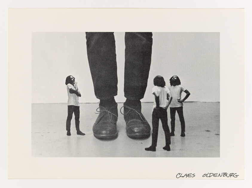 Three small men stand and look up at a pair of oversized shoes and legs.