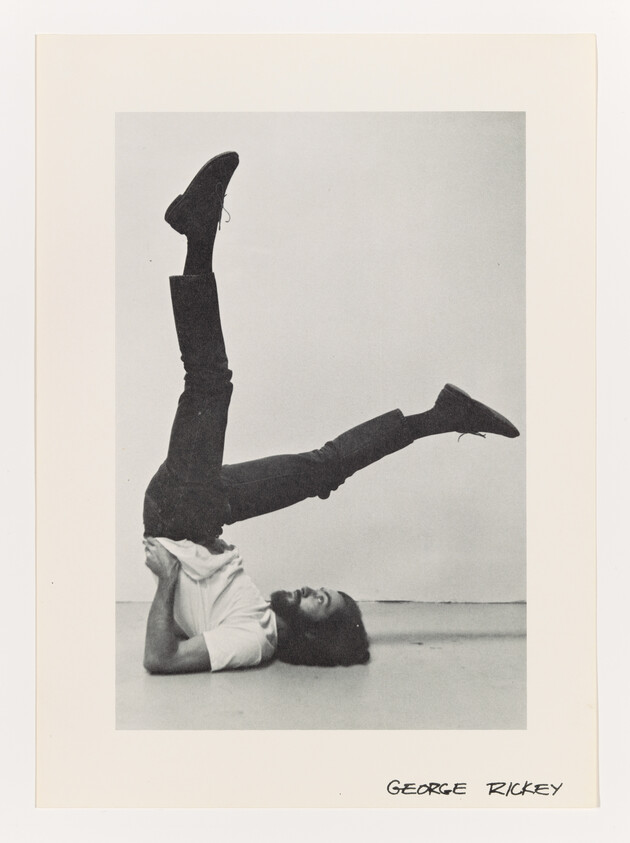 A man lies on his shoulders with his legs raised in a playful acrobatic pose.