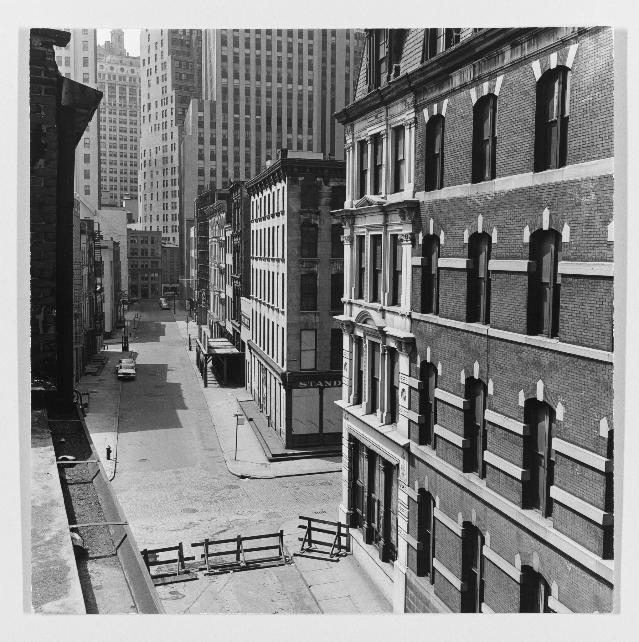 Empty city street with large brick building on the right and wooden barricades blocking the intersection.