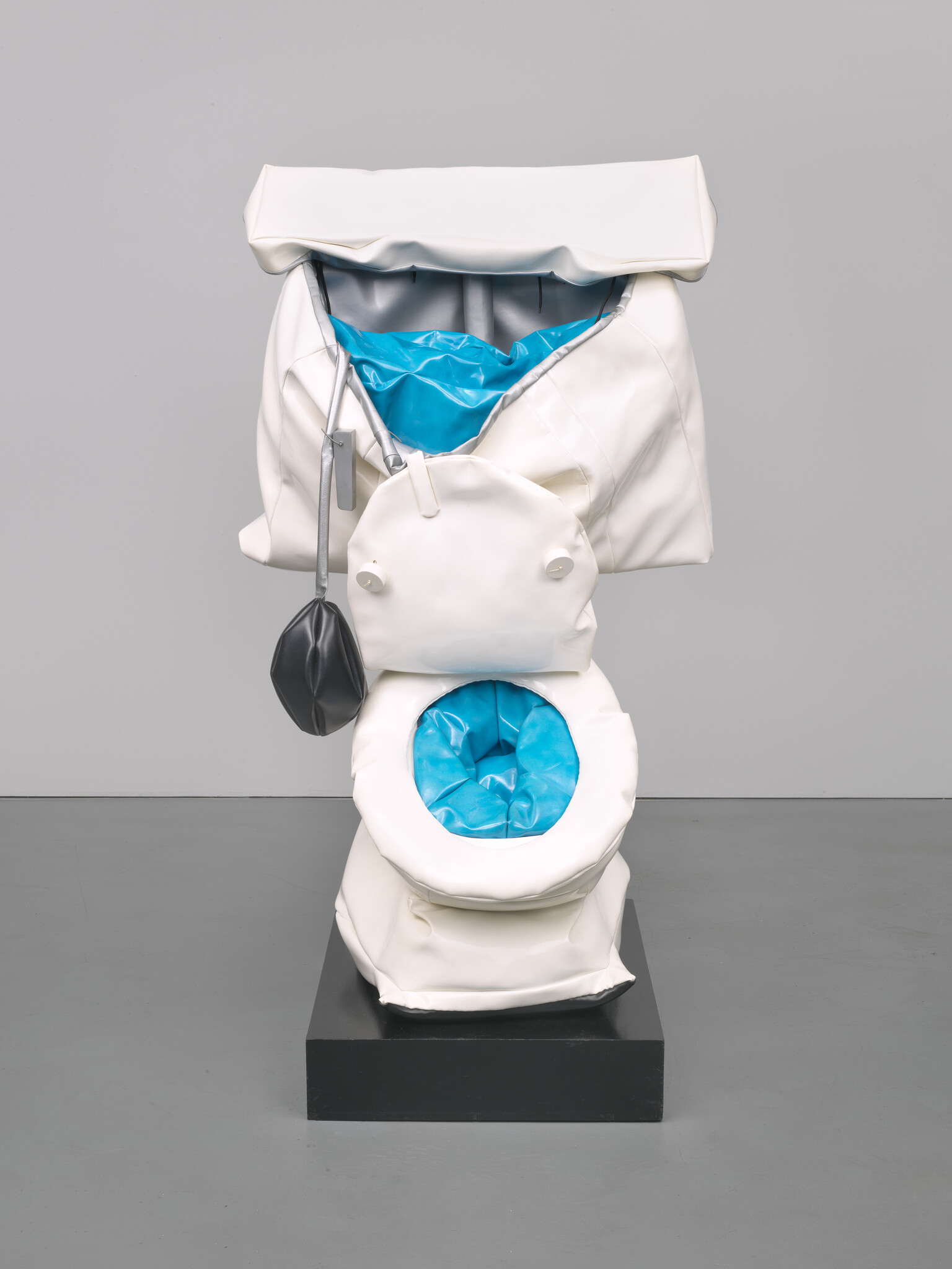 A soft white sculptural toilet with bright blue inner lining sits on a black pedestal.