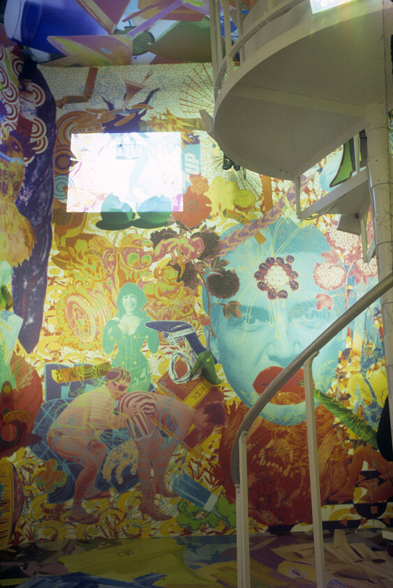 A colorful psychedelic mural covers the wall while a white spiral staircase curves in front.