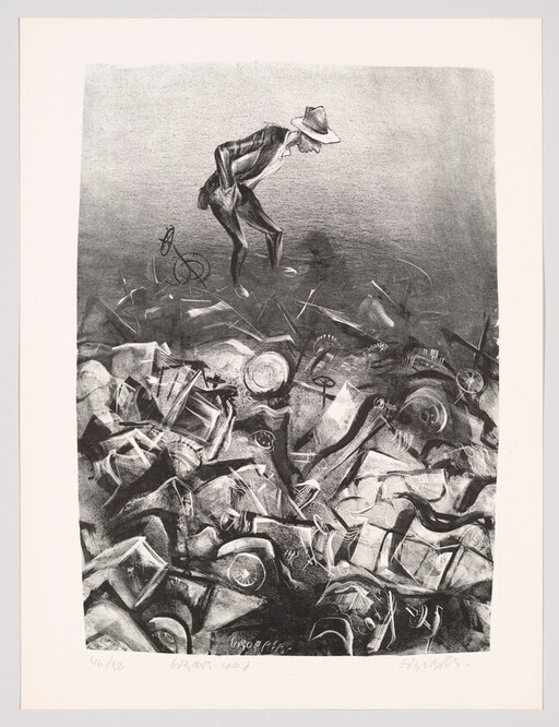A man in a hat stands on a large pile of discarded machinery and looks down.